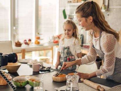 Une maman influenceuse avec sa fille en train de cuisiner ensemble pour poster une vidéo sur les réseaux sociaux